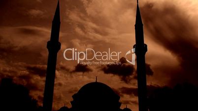 Time lapse clouds flowing past silhouetted twin minaret mosque 4