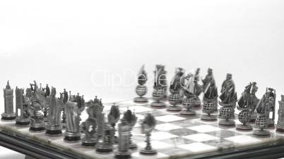 Silver chess pieces on board rotate