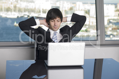 Zufriedener Geschäftsmann lehnt sich zurück vor seinem Computer nach einem guten Verkauf