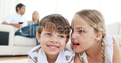 Little girl telling a secret to her brother