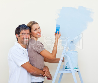 Smiling lovers painting a room