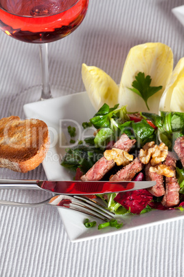 gemischter Salat auf einem weißen Teller mit einem Glas stieg