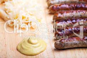 Bratwurst, Senf und Sauerkraut auf einer Holztafel