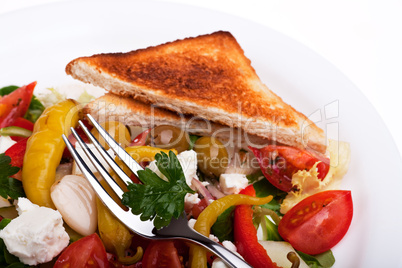 Griechischer Salat auf einem Teller mit einer Scheibe Toastbrot