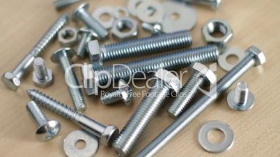Rotating bolts and nuts on workbench.