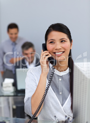 Confident asian businesswoman on phone at her desk