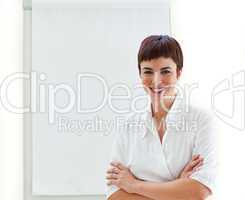 Young businesswoman with folded arms in front of a board