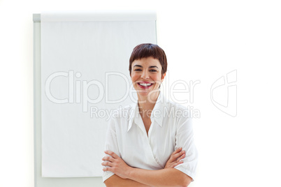 Laughing businesswoman with folded arms in front of a board