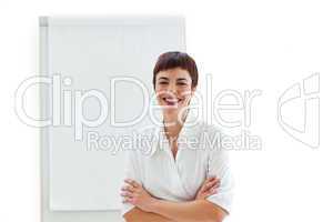 Laughing businesswoman with folded arms in front of a board