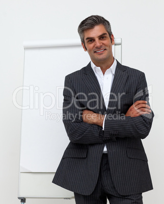 Businessman with folded arms in front of a board