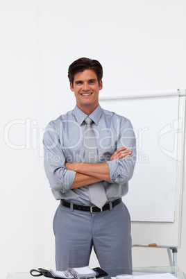 Charming businessman with folded arms in front of a board