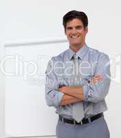 Smiling businessman with folded arms in front of a board