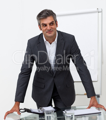 Smiling mature businessman leaning on a conference table