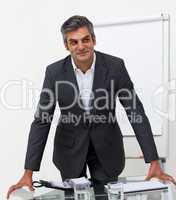 Smiling mature businessman leaning on a conference table