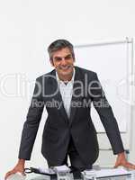 Assertive businessman leaning on a conference table