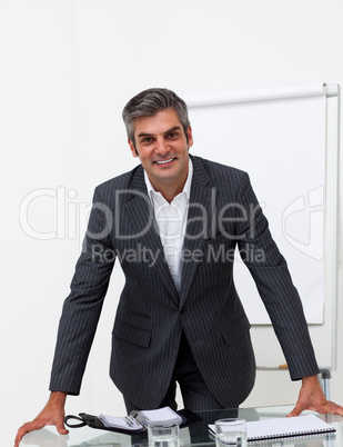 Charming businessman leaning on a conference table