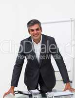 Charming businessman leaning on a conference table
