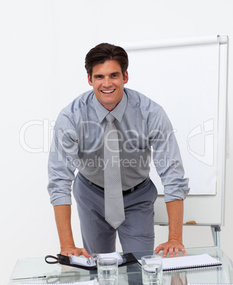 Cheerful businessman leaning on a conference table