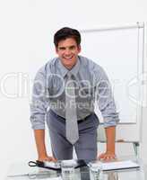 Cheerful businessman leaning on a conference table