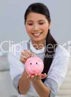 Smiling businesswoman saving money in a piggybank