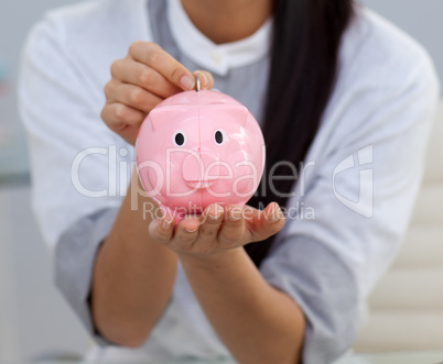 Close-up of a businesswoman saving money in a piggybank