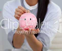 Close-up of a businesswoman saving money in a piggybank