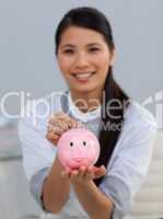 Young ethnic businesswoman saving money in a piggybank