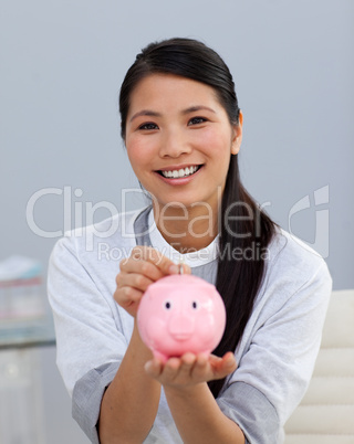 Charming asian businesswoman saving money in a piggybank