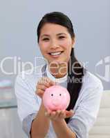 Charming asian businesswoman saving money in a piggybank