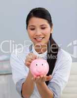Asserive businesswoman saving money in a piggybank
