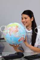 Smiling asian businesswoman looking at a globe