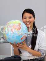 Assertive asian businesswoman holding a globe