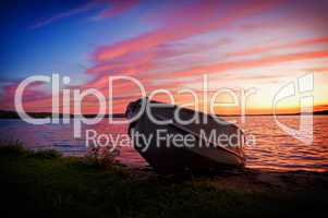 Image of fishing boat on shore of lake at sunset