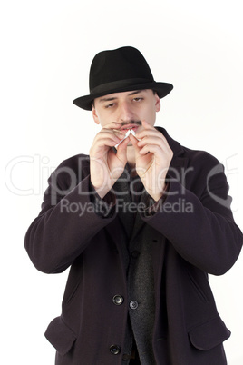 Man in hat breaking a cigarette