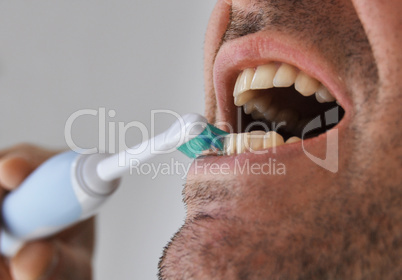 Man brushing his teeth with electric toothbrush