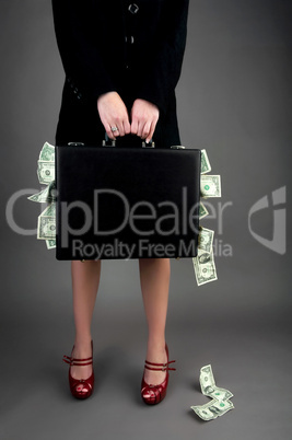 Woman holding briefcase overflowing with money