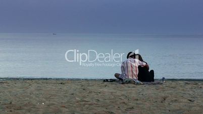 Young lovers sitting on the beach at dawn