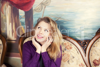 Sexy blond girl sitting on a luxury sofa looking up