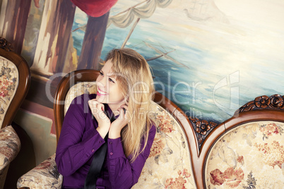 Sexy blond girl sitting on a luxury sofa looking away