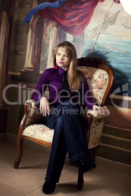 Sexy blond girl sitting on a luxury armchair