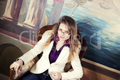 Sexy blond girl with glasses sitting on a luxury armchair