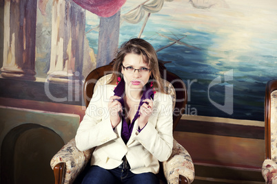 Sexy blond girl with glasses sitting on a luxury armchair