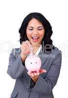 Happy ethnic businesswoman saving money in a piggybank
