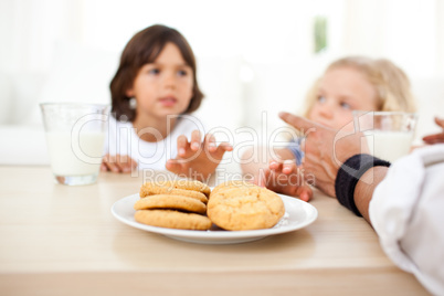 Siblings eatings biscuits and drinking milk