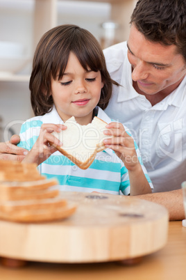 Little boy eating a sandwich with his father