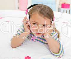 Adorable gril listening to music lying on her bed
