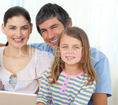 Little girl using a laptop with her parents