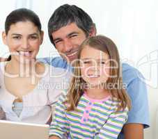 Little girl using a laptop with her parents