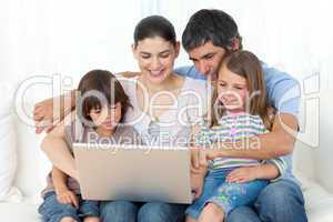 Jolly family using a laptop on the sofa