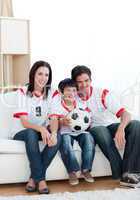 Jolly young family watching a football match